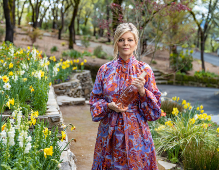 Leslie Frank holding a bottle of Leslie Rosé in her garden