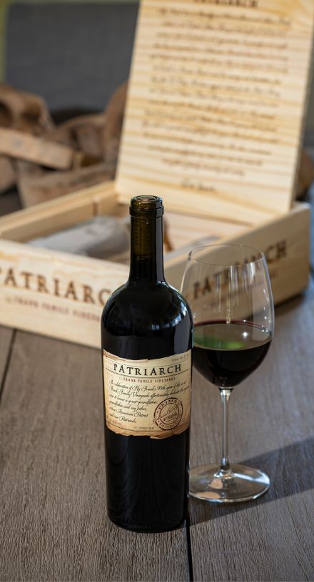 A bottle of Frank Family's Patriarch in front of a wood cellar box