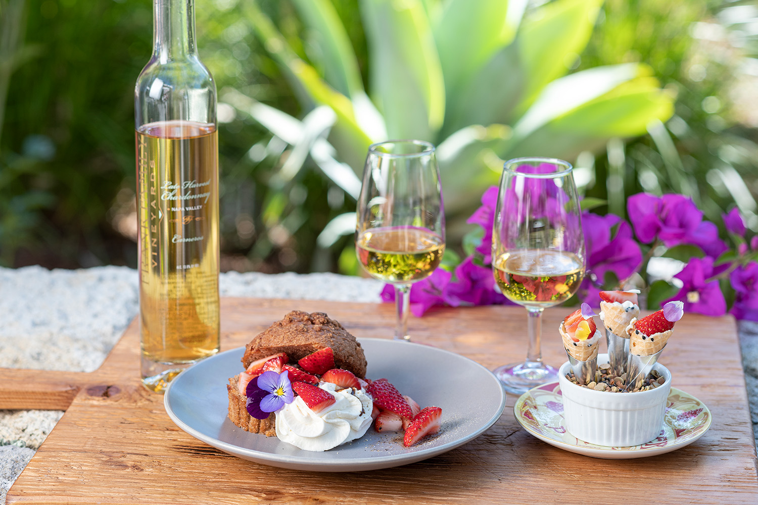 A bottle of Frank Family's Late Harvest Chardonnay next to strawberry shortcake, strawberry cones, and two glasses of wine