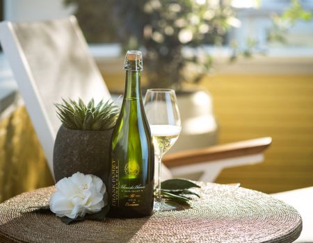 A bottle of Frank Family's Blanc de Blancs and flute sitting on a sunny porch