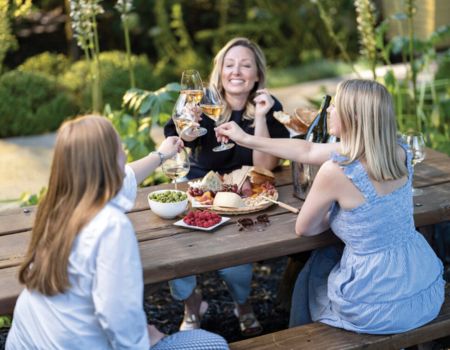 Three women enjoying a picnic at Frank Family's picnic tables 