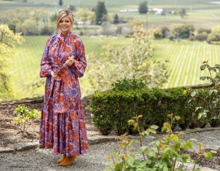 Leslie Frank holding a bottle of Leslie Rosé with views of Napa Valley behind her