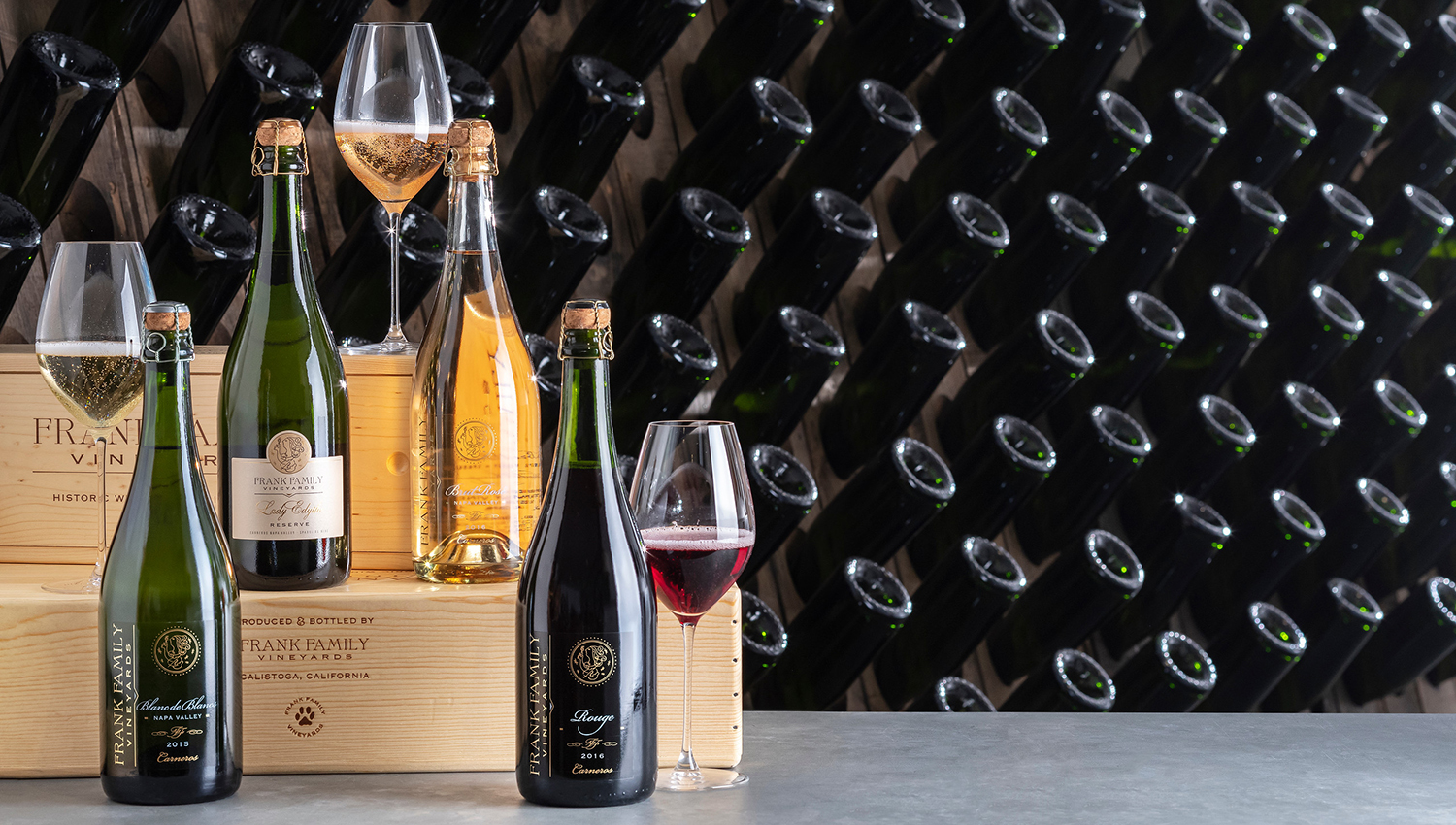 An assortment of sparkling wines in front of riddling racks in the winery