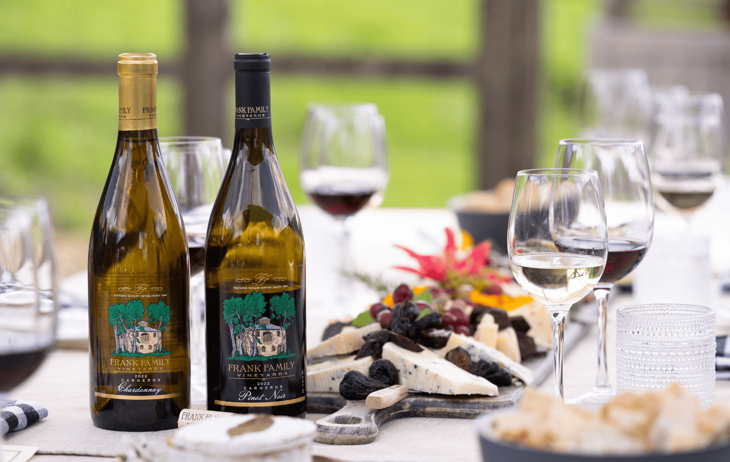 A bottle of Chardonnay and Pinot Noir in front of a charcuterie spread.