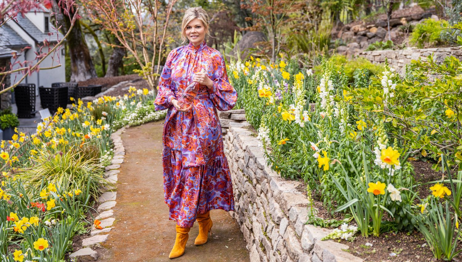 Leslie Frank holding a bottle of Leslie Rosé in a bed of daffodils