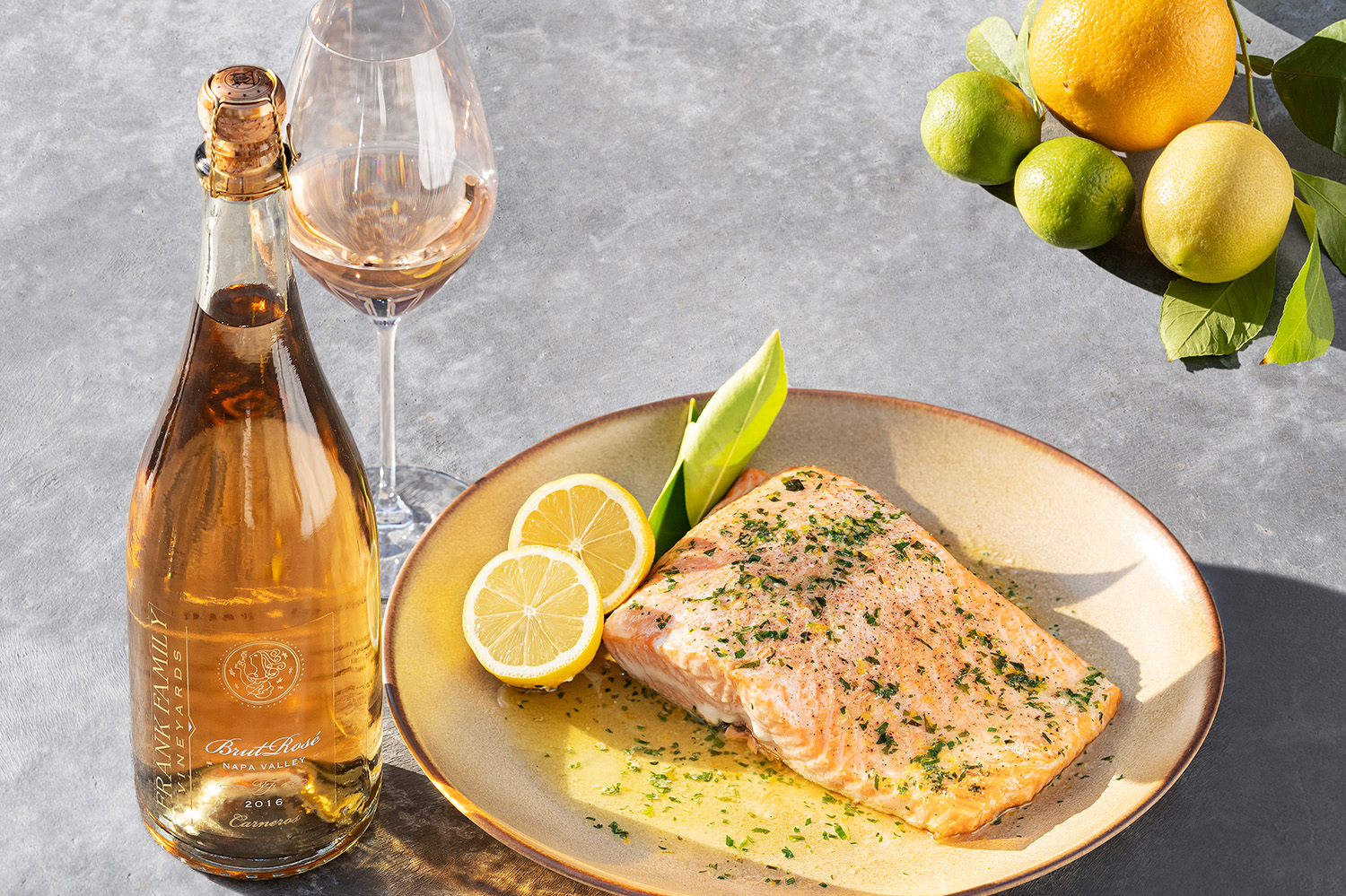 A dish of roasted salmon beside a glass of Brut Rosé and fresh lemons