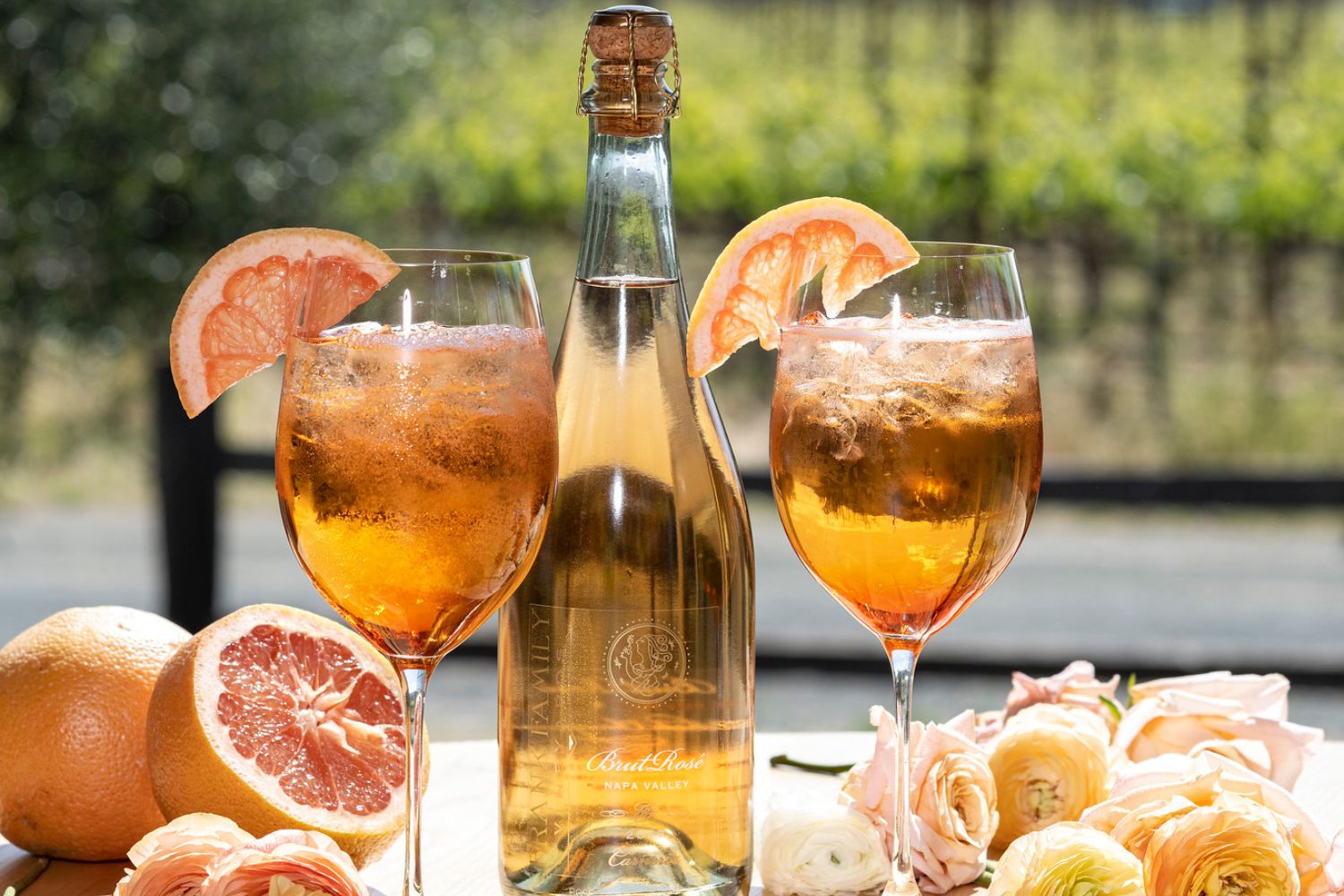 Two glasses of rosé aperol sptriz garnished with grape fruit segments.