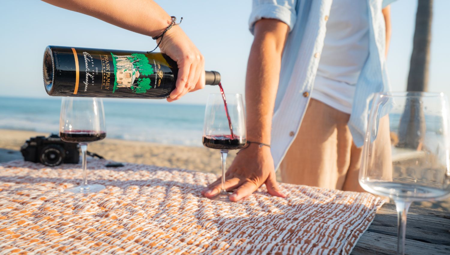 A bottle of Napa Valley Cabernet being poured into a glass on the beach