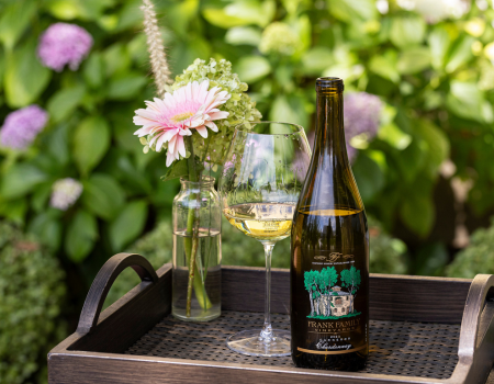 A bottle of Frank Family Carneros Chardonnay posed on a tray with a flower vase. 