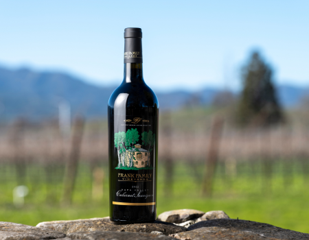 A bottle of Frank Family's 2022 Napa Valley Cabernet with Benjamin Vineyard in the background. 